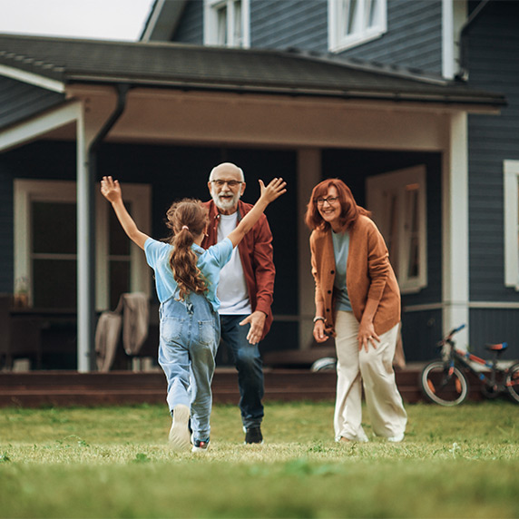 granddaughter running toward her grandparents in their yard life insurance for retirement
