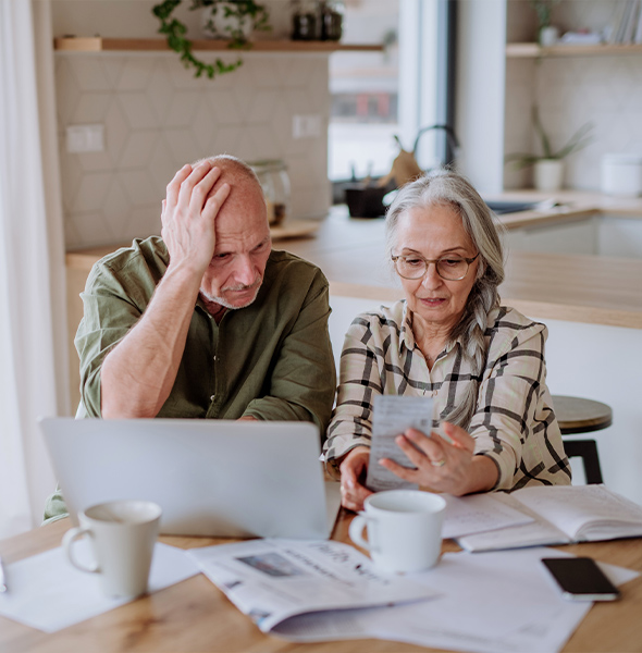 senior couple sitting at kitchen table reviewing bills for their retirement budget will you have enough to retire