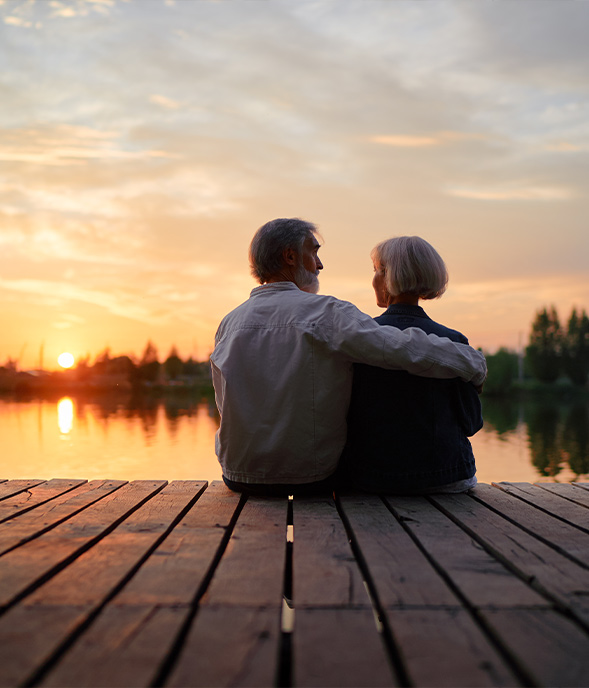 senior couple sitting on dock by the water watching the sun set retirement income strategy